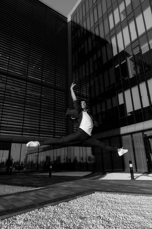 young attractive dancer in casual cloth doing ballet jump on the urban background. Contemporary...