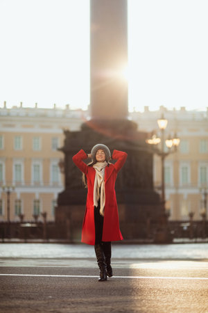Girl in a red coat wearing a fur hat posing in snowの写真素材