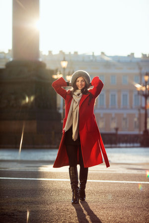 Girl in a red coat wearing a fur hat posing in snowの写真素材