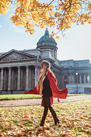 Girl in a red coat wearing a fur hat posing in snowの写真素材