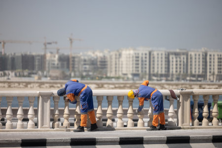 Two unrecognizable men painting a fence working at construction siteの写真素材