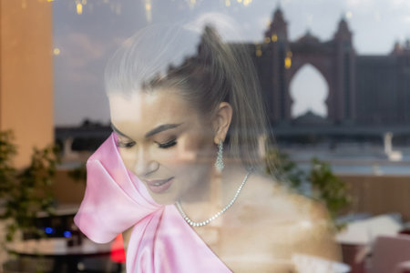 A very beautiful girl smiles in the window among the flowers. Womans happiness. Attractive...