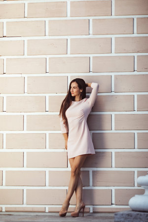 beautiful young woman against white brick wallの写真素材