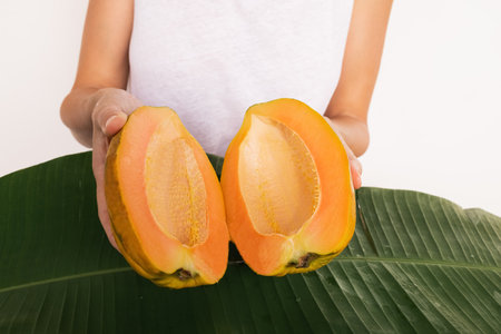 two Half of papaya fruit on banana leaves. Fragrant tropical fruit pulp. Sweet fresh papaw, raw vegan food. papaw pawpaw mountains Vasconcellea pubescens of South America, India, Myanmar, Thailand powの写真素材