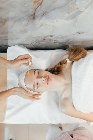 Close-up of the process of a beautician applying oil to a womans face with a pipette Facial skin care with medicated cosmetic oil. hold professional cure serum bottle oil treatment cosmetologistの写真素材