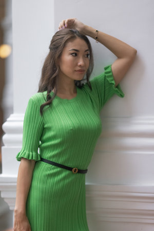 An elegant and beautiful Asian model in a green dress strikes a pose thats both graceful and captivating. Her dark hair, beautiful lips, and attractive facial features make for an alluring imageの写真素材