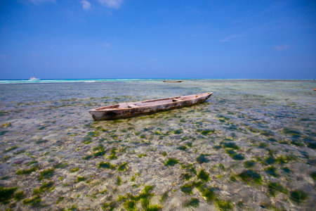 The scene depicts an aged wooden boat gently floating on the crystal-clear waterの写真素材