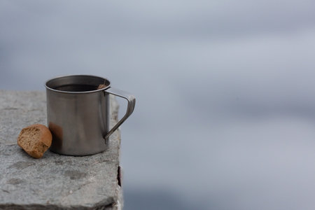 An image of a steel camping cup and bread on a backdrop of clouds.の写真素材
