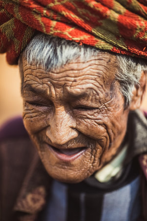 Very old man menr portrait with emotions. Grandfather happy and smiling. Close-up of a pensive old man in woven bamboo hat sitting alone outdoors at summer. Gorontalo, Indonesia - Oktober 16, 2006.のeditorial素材