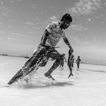 ZANZIBAR, TANZANIA - January 2021: Handsome man runs with a rich catch in his hands. Success. Male power. The energy of victory. Fishingのeditorial素材