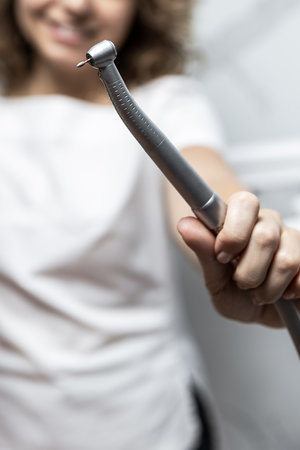 Dentist hand with drill illustrates operation of dentist dental drill machine with water. Dentists hands with working with dental drill in dental office. Close up, selective focusの写真素材