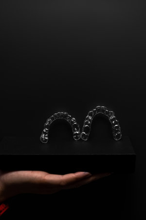 Two orthodontic aligners held by a hand in the dental office. Dental props.の写真素材