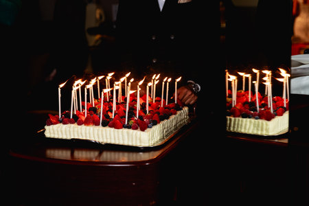 A birthday fruit cake with lots of small candles.A cake with fresh strawberries.の写真素材