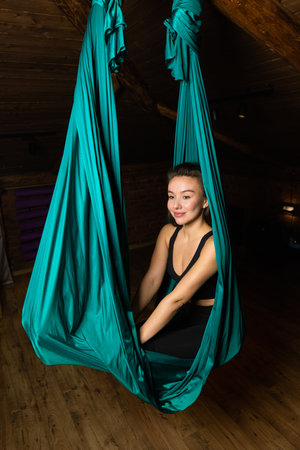 Training on a hammock with a beautiful girl. Fly yoga in the gym. Aero yoga.の写真素材