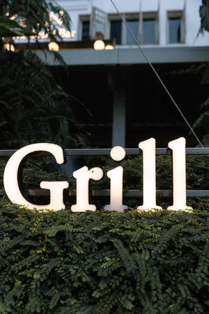 The sign Grill lights up in the evenings, green plants are around