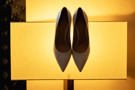 Beige high-heeled shoes with a pointed end in the studio on a yellow background.の写真素材