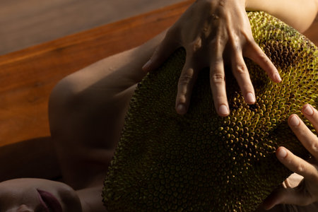 Person holds jackfruit in their hands.