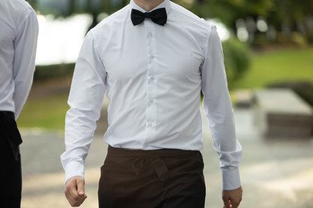 An elegant man in a suit outdoors or a waiter at a festive event.の写真素材