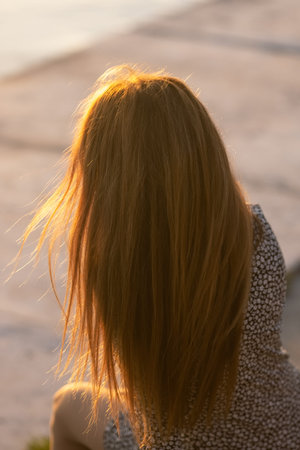 A beautiful girl admires the sunset, the girls face is not visible