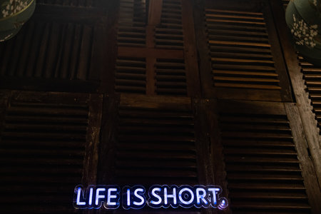 The neon sign on the wall says LIVE IS SHORT.の写真素材