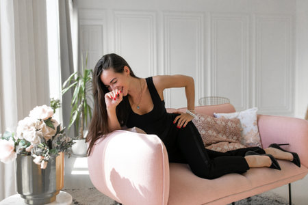 Happy peaceful young woman relaxing on comfortable couch at home with closedの写真素材
