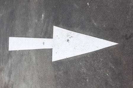 A large arrow pointing to the right, painted in white on an asphalt road. Road markings in the city.の写真素材