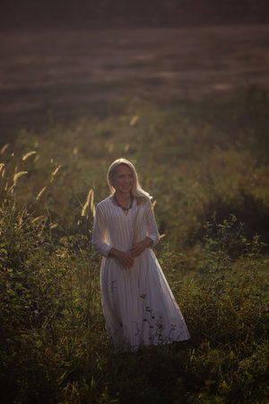 A beautiful fifty-year-old woman with light hair, dressed in white clothingの写真素材