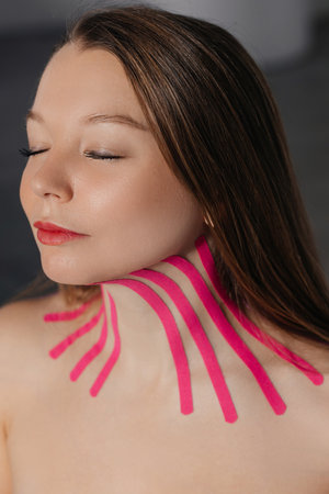 Tape for a facelift. Yong neck. Taping. Salon or home procedures therapeutic medicine tapes on neck of a young womanの写真素材