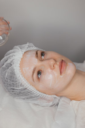 process of applying a cream before a facial aesthetic treatment to prepare the skin. This step hydrates, soothes, and protects the skin, ensuring better results and minimizing irritationの写真素材