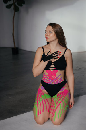 Kinesiology tapes on the abdomen, arms, and chest of a woman with long hair. Tapes for body shaping.の写真素材
