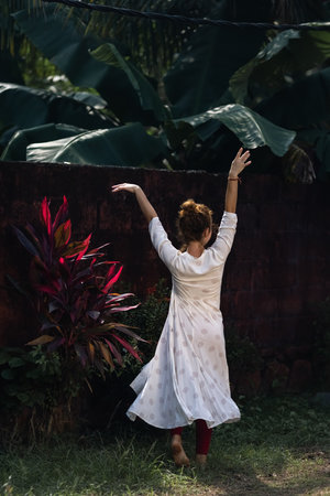 Red haired Caucasian girl is dancing in an Indian white dress. The woman is spinning in dance. Traveling in India.の写真素材