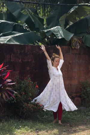 Red haired Caucasian girl is dancing in an Indian white dress. The woman is spinning in dance. Traveling in India.の写真素材