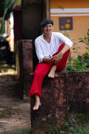 An attractive man in a hat and red pants is looking at the camera. Handsome maleの写真素材