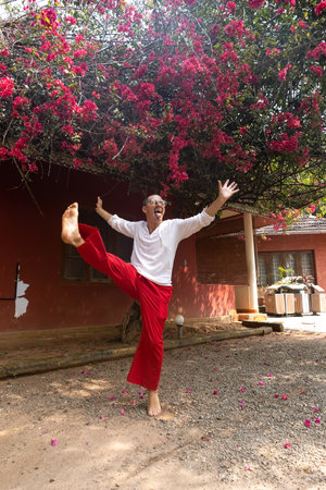 A cheerful and attractive man wearing red pants and a white T-shirt is jumping high with joy. Summer has come and its time for a vacation in the great outdoors.の写真素材