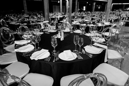 Black and white photo of a stylishly set round black table with elegant tableware at a formal event.の写真素材