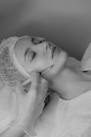 Black and white photo of woman with fair skin receiving botox injections during a cosmetic procedureの写真素材