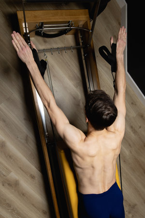 Slim male ballet dancer trains on Pilates equipment. Elegant pose, core strength, body controlの写真素材