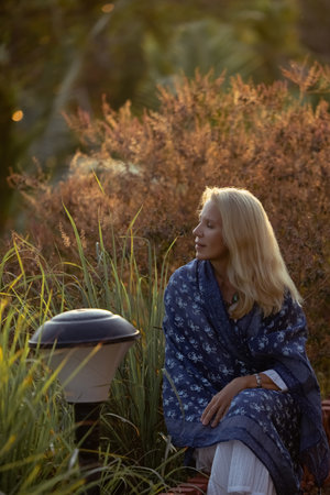 Beautiful mature woman in blue dress at sunset, natural elegance and anti-aging concepの写真素材