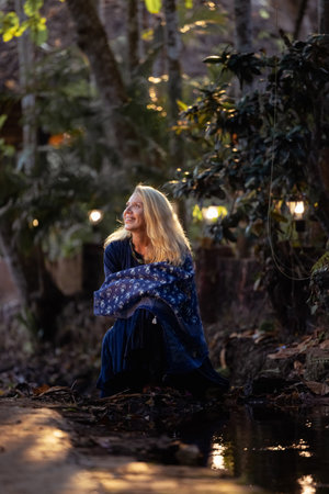Beautiful mature woman in blue dress at sunset, natural elegance and anti-aging concepの写真素材