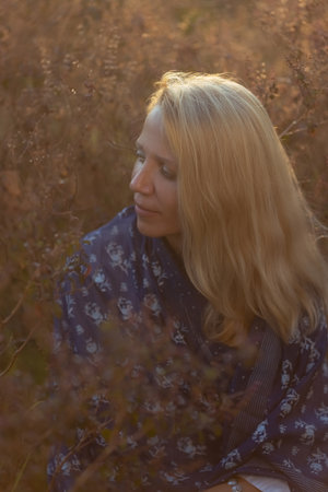 Beautiful mature woman in blue dress at sunset, natural elegance and anti-aging concepの写真素材
