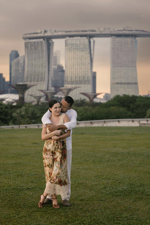 Close-up of an international couple embracing in front of Marina Bay Sands in Singapore. Asian man and Eastern European woman share a romantic moment outdoors, stylish and emotional atmosphere.の写真素材