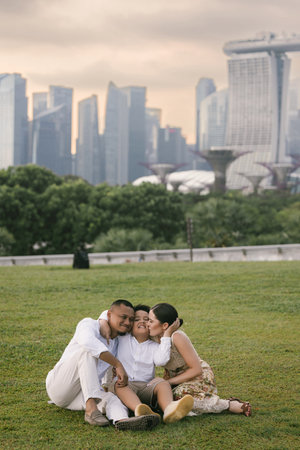 Happy international family of three posing in front of tall modern skyscrapers. Asian father, Eastern European mother, and their 7-year-old mixed-race child enjoying time together in the city.の写真素材