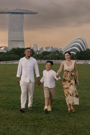 Elegant international family in Singapore. Asian father, Eastern European mother, and their child smiling near Marina Bay Sands. Diverse background and warm, joyful family moment outdoorsの写真素材