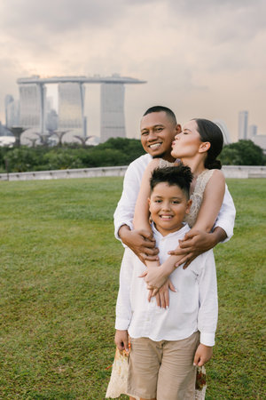 Elegant international family in Singapore. Asian father, Eastern European mother, and their child smiling near Marina Bay Sands. Diverse background and warm, joyful family moment outdoorsの写真素材
