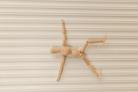 Wooden mannequin figure showing a backflip or capoeira dance move on a white background.の写真素材