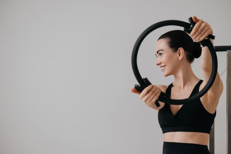 Smiling young woman holding a pilates ring in hands while doing pilates trainingの写真素材