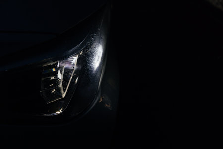 Modern car headlight glowing brightly on a black backgroundの写真素材