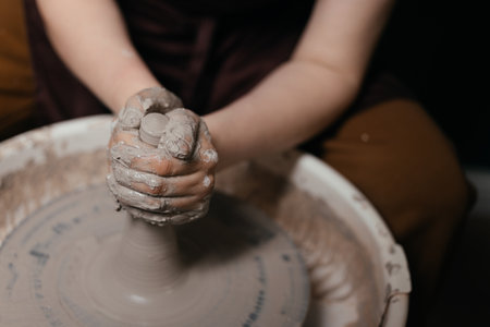 Potter shaping a ceramic artwork on a wheel. Hands in clay. Artistic pottery workshopの写真素材