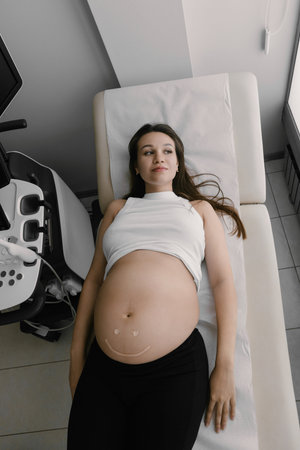 Portrait of beautiful pregnant Caucasian brunette with long hair in gynecology office