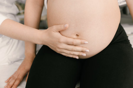 Female doctor examining pregnant woman by hand on abdomen